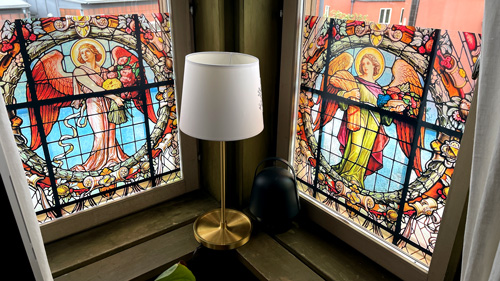 Ett hörn med två fönster och båda har FarbenFensterbilder med årstidsänglar